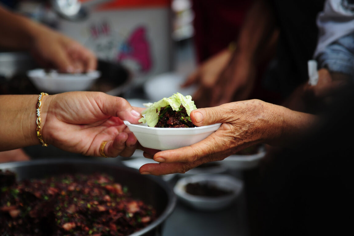 A bowl of food exchanges hands from one person to another.