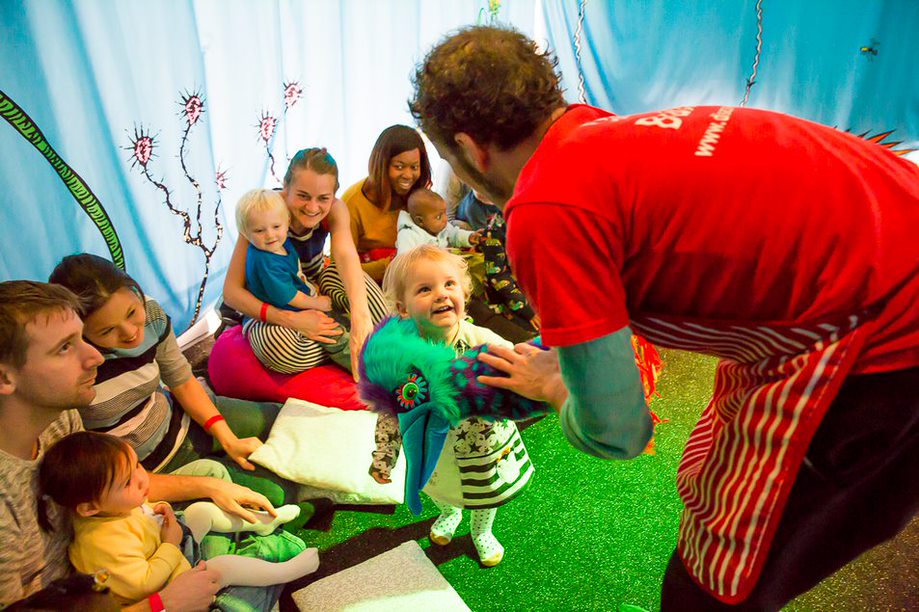 A Family Arts Network event with children and their families sat together in a blue tent.