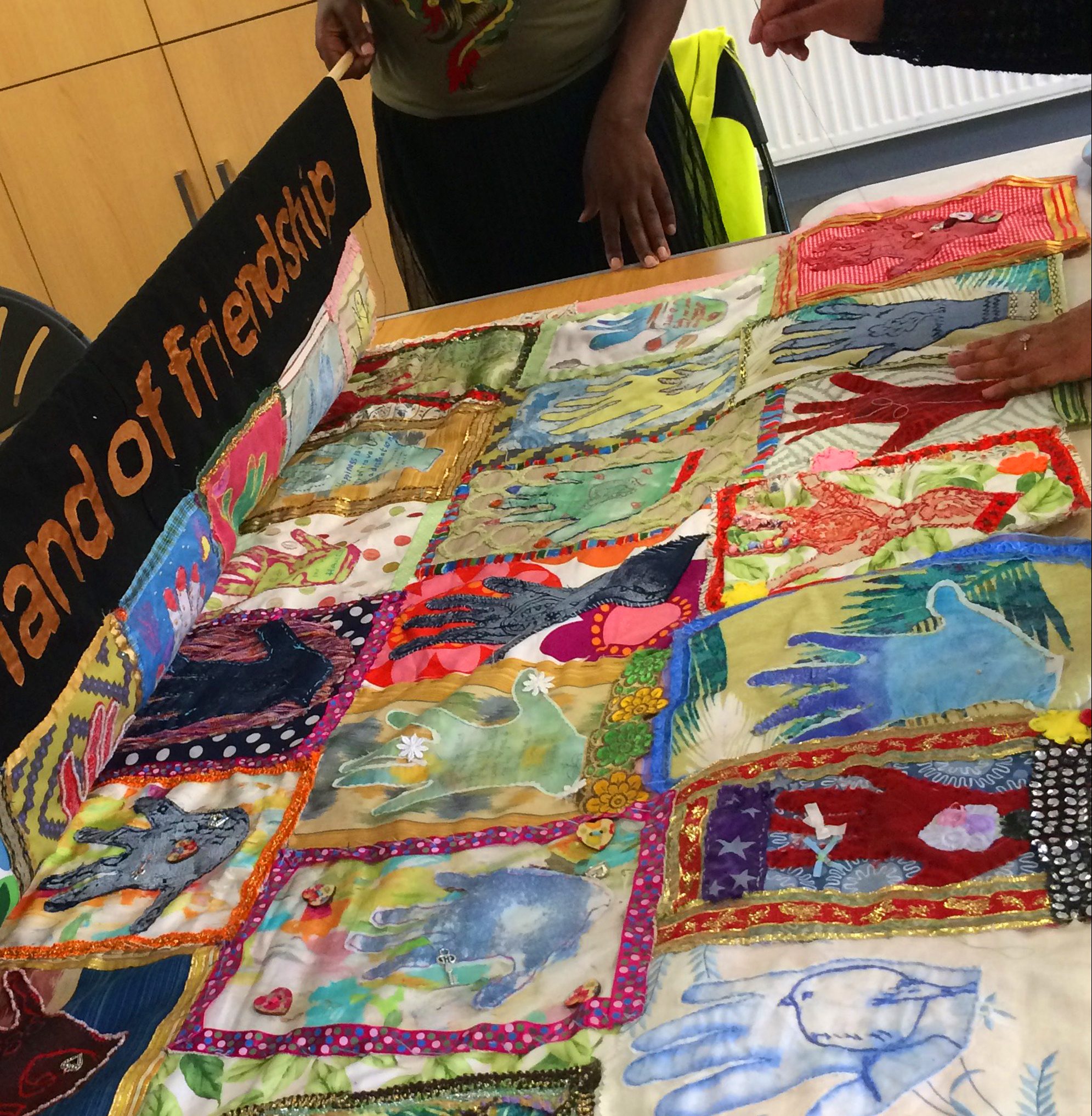 Multi-coloured artwork made out of fabric displayed on a table.