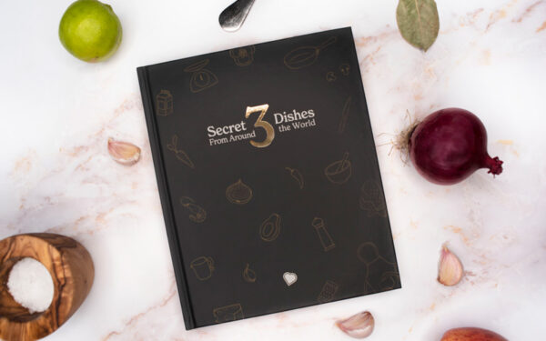 The front cover of Bounceback's third cookbook - navy with a gold 3 and the title Secret Dishes From Around the World 3