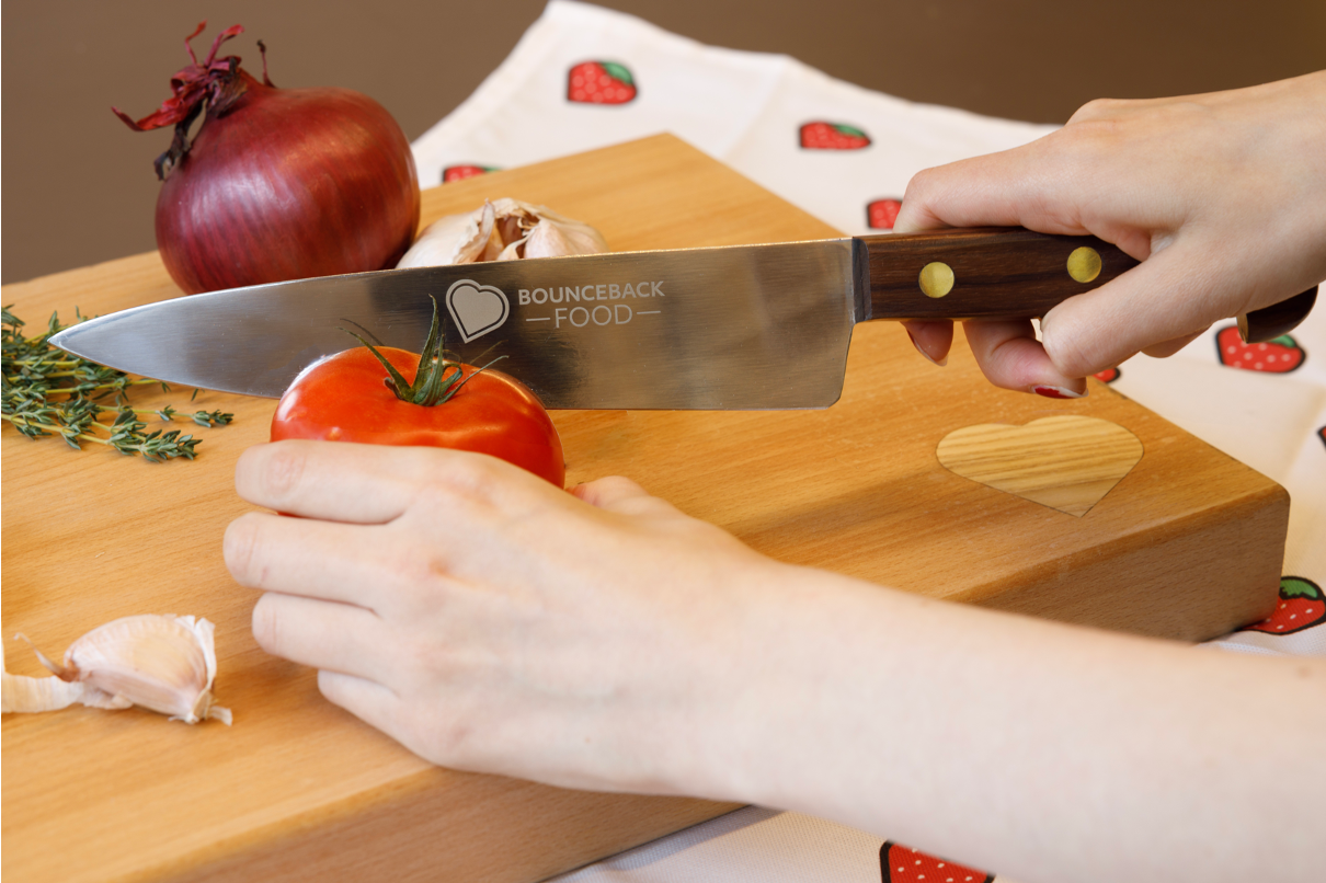 A knife is slicing through a wooden chopping board with the Bounceback logo in the bottom right corner.