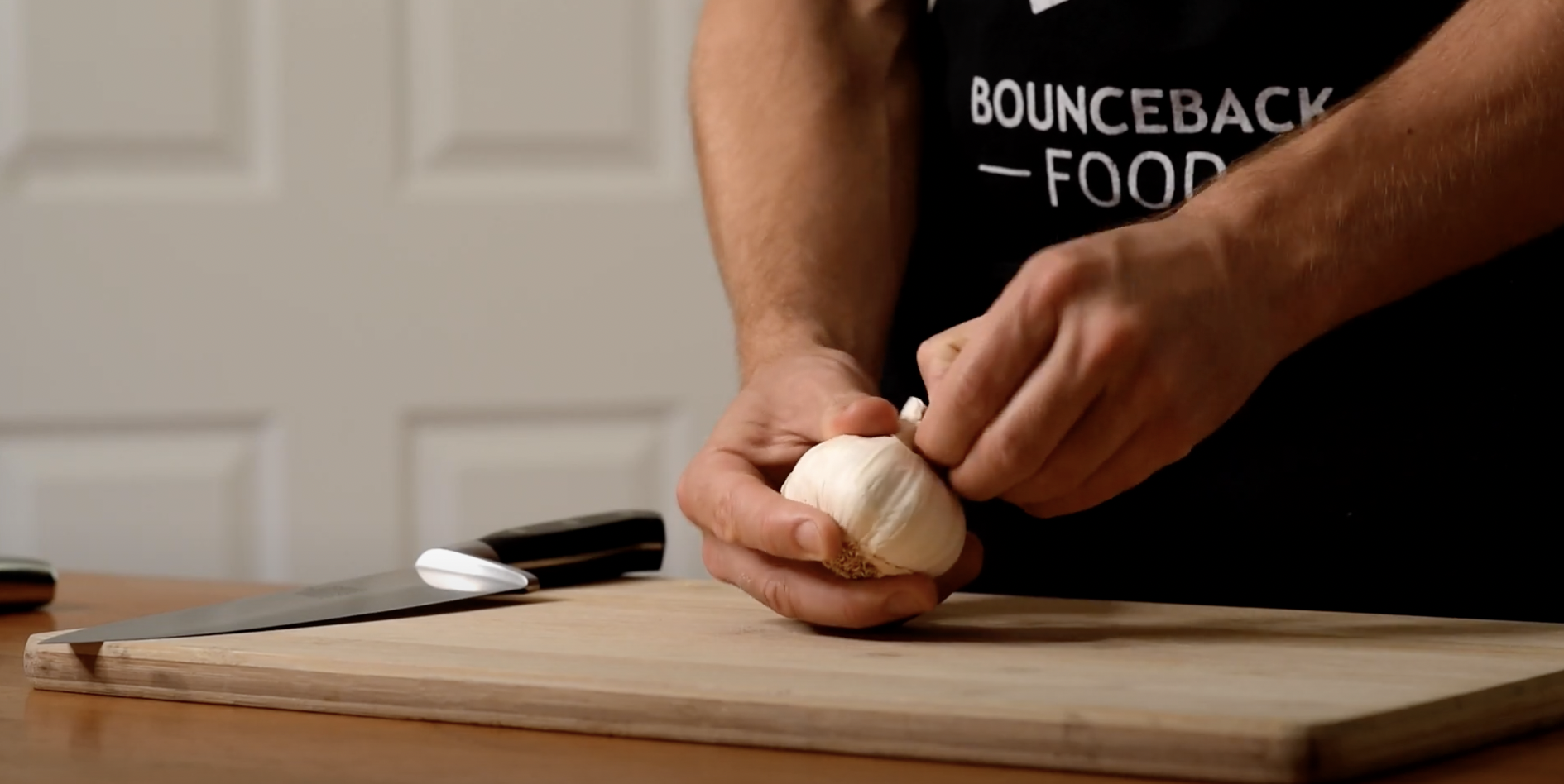 A Bounceback Food chef preparing garlic on a chopping board.