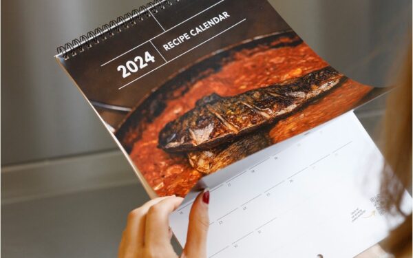 A woman opens the 2024 fundraising recipe calendar.