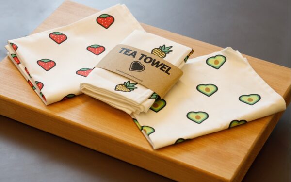 3 tea towels placed on top of a Bounceback branded chopping board.