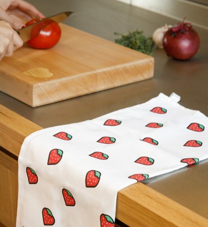 A tea towel with a strawberry pattern on a kitchen surface.