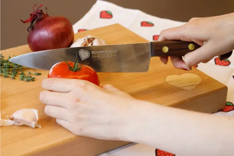 a close up of someone cutting into a tomato using a Bounceback Food knife